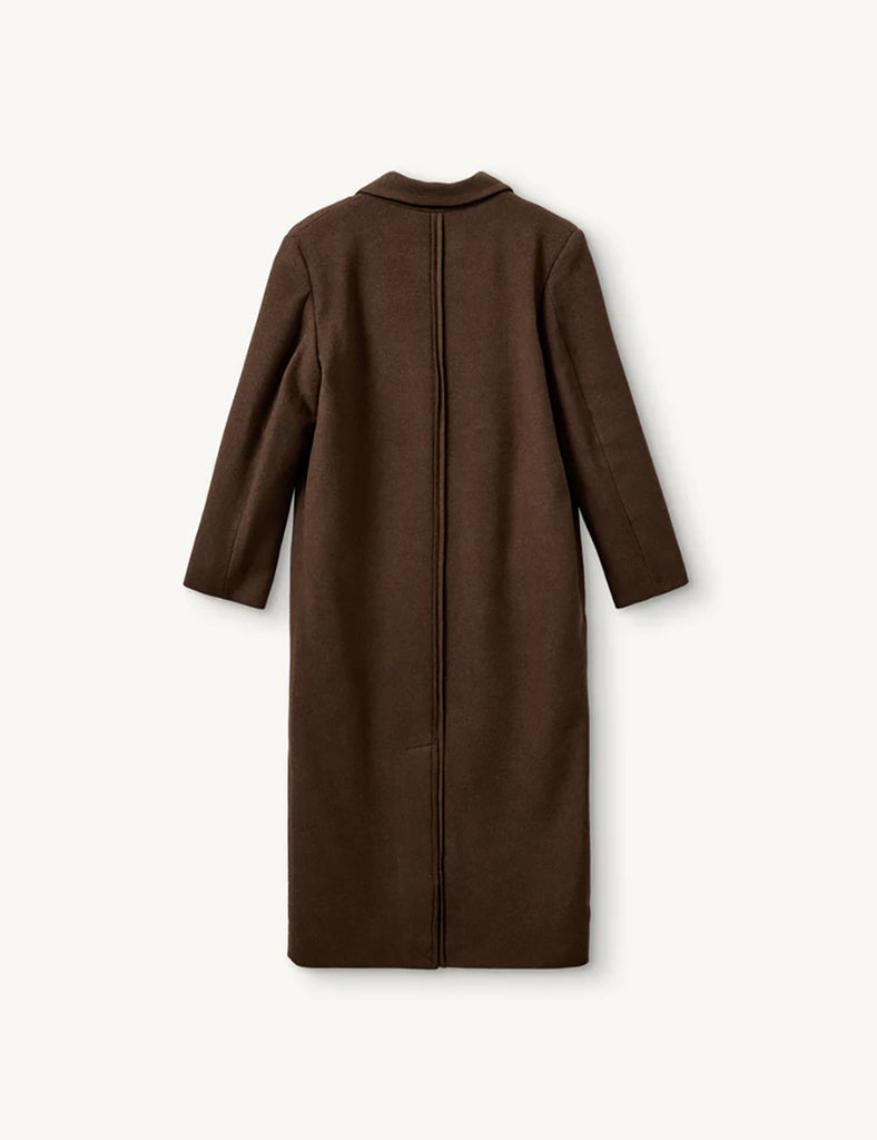 Elegancki, prosty płaszcz Clooney Man Brown w pięknym, czekoladowym kolorze z klasycznym kołnierzem i bocznymi kieszeniami. Płaszcz ma prosty krój i długość przed kostki. Zapinany z przodu na guziki. Posiada podszewkę. To ponadczasowy, klasyczny fason idealny na chłodniejsze jesienne i zimowe dni. Wykonany z mieszanki wełny z recyklingu.&nbsp;