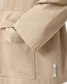 Cienki, krótki, beżowy płaszcz Short coat 97949 CLOSED o luźnym fasonie i prostym kroju. Posiada szerokie, długie rękawy, kołnierzyk i duże, przednie kieszenie z klapkami. Zapinany za pomocą zatrzaskowych guzików