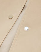 Cienki, krótki, beżowy płaszcz Short coat 97949 CLOSED o luźnym fasonie i prostym kroju. Posiada szerokie, długie rękawy, kołnierzyk i duże, przednie kieszenie z klapkami. Zapinany za pomocą zatrzaskowych guzików