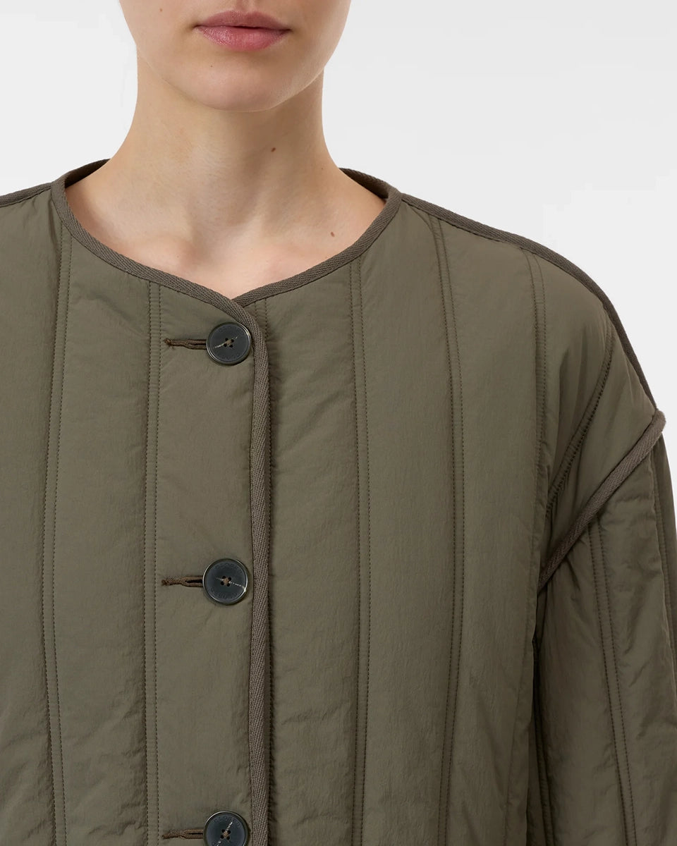 Krótka, pudełkowa, pikowana kurtka Quilted CLOSED z okrągłym dekoltem i opadającymi ramionami. Zapinana na guziki. Z boku posiada niewielkie rozcięcia oraz dwie, boczne kieszenie. Jest dłuższa z tyłu.