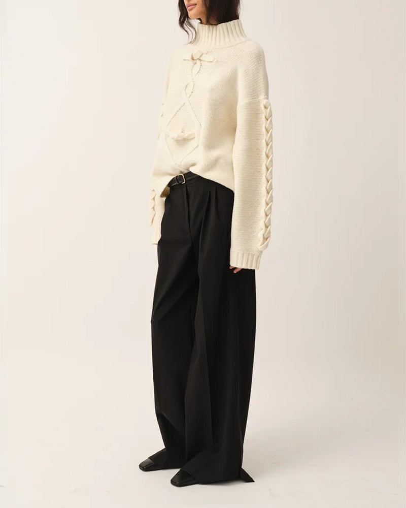 Luźny, gruby, kremowy golf Como Braid The Garment z pięknymi, warkoczowymi i wzorami. Posiada opadające ramiona i szeroki, zaokrąglone rękawy. Wykończony ściągaczami o prążkowanej fakturze. Sweter ma długość za biodra. Wykonany bardzo ciepłej i miękkiej, wełnianej dzianiny z kaszmirem. 