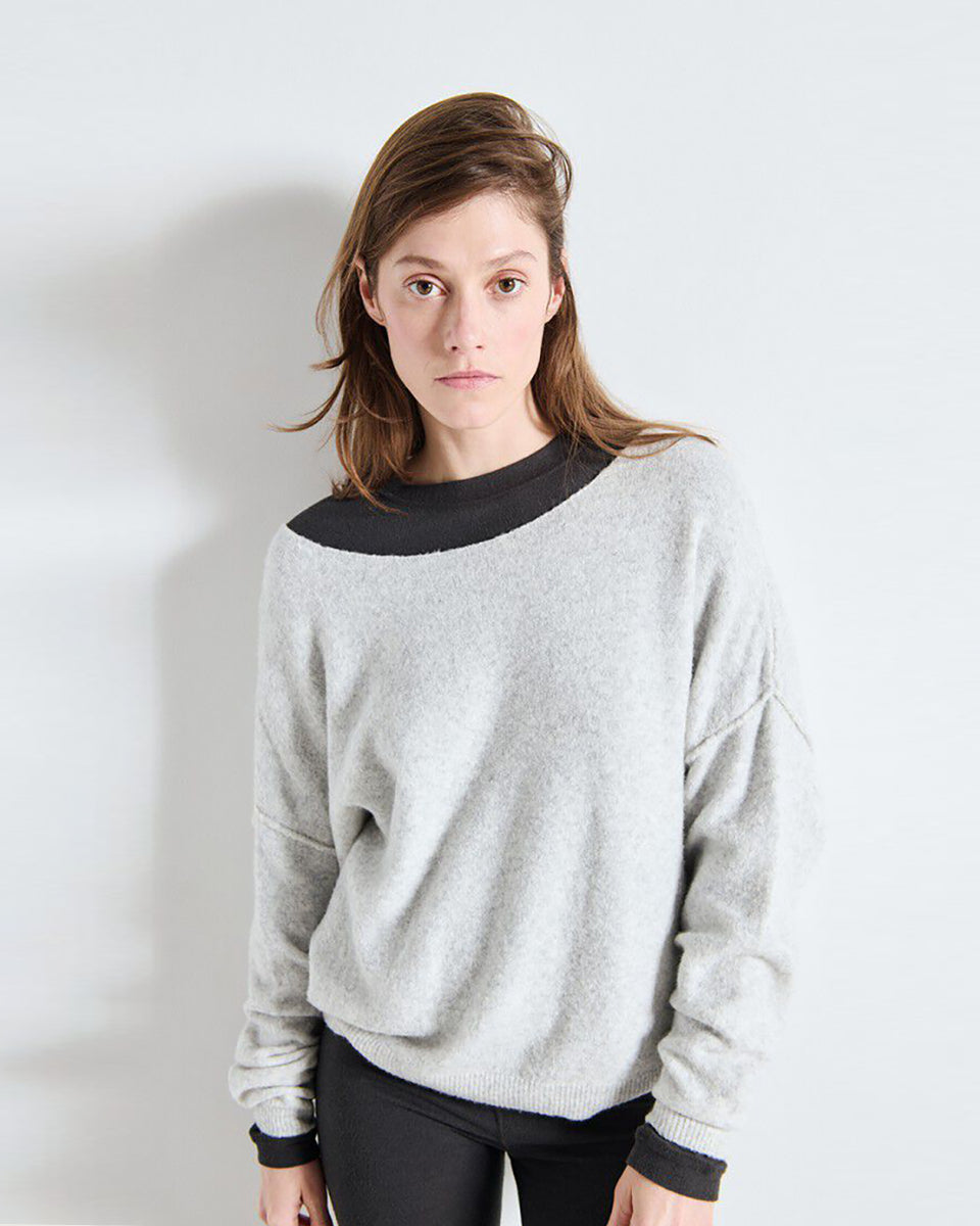 Luźny sweter DAM225 American Vintage Gris Chine w jasnoszarym melanżowym kolorze. Ma obniżoną linię ramion i szeroki, łódkowaty dekolt wykończony surowym brzegiem. Na plecach widoczne jest pionowe przeszycie biegnące przez środek. Materiał ma wyraźną, lekko ziarnistą strukturę przypominającą dzianinę o drobnym splocie. Wykonany z mieszanki z poliamidem i wełną.

-Luźny krój

-Obniżona linia ramion

-Dekolt łódka

-Zamów sweter w swoim standardowym rozmiarze