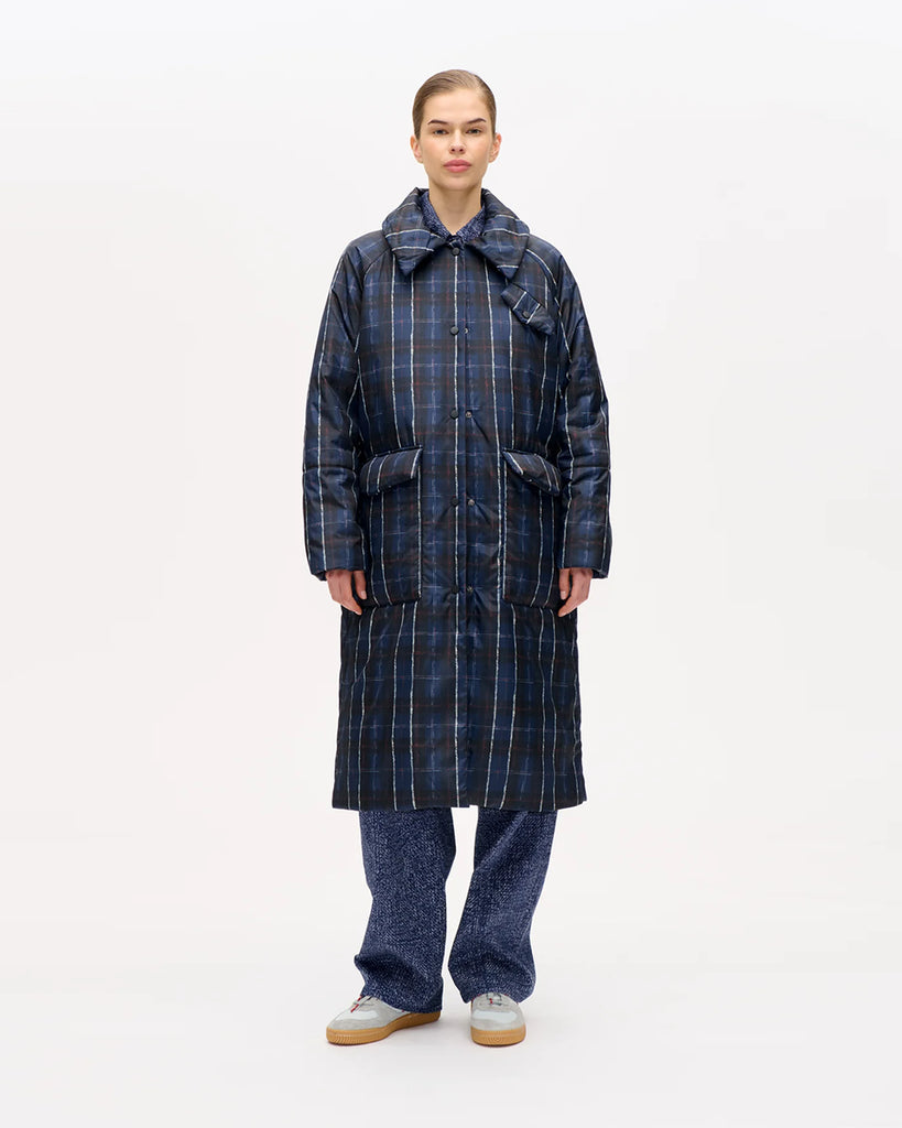 Długi, puchowy płaszcz Deana Navy Check o luźnym kroju z kołnierzem, elastycznymi ściągaczami przy mankietach, kieszeniami i rozcięciem z tyłu. Zapinana na napy. Posiada kieszeń na piersi i dwie kieszenie naszywane po bokach. Długość midi.
