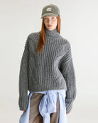 Szary sweter z golfem Deteo Mid Grey marki Bellerose o kroju oversize. Wykonany ściegiem typu "full cardigan", wyróżnia się bardzo grubym splotem ściągaczowym oraz dużymi wzorami warkoczowymi korpusie i rękawach.

-Krój oversize: celowo powiększony fason zapewniający obszerną, luźną sylwetkę

-Golf

-Warkoczowy splot&nbsp;