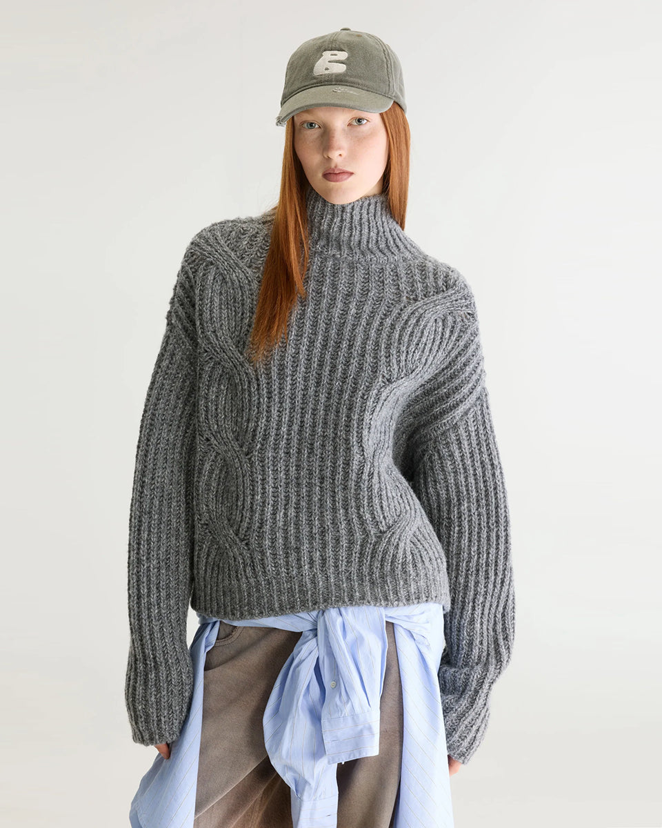 Szary sweter z golfem Deteo Mid Grey marki Bellerose o kroju oversize. Wykonany ściegiem typu "full cardigan", wyróżnia się bardzo grubym splotem ściągaczowym oraz dużymi wzorami warkoczowymi korpusie i rękawach.

-Krój oversize: celowo powiększony fason zapewniający obszerną, luźną sylwetkę

-Golf

-Warkoczowy splot&nbsp;