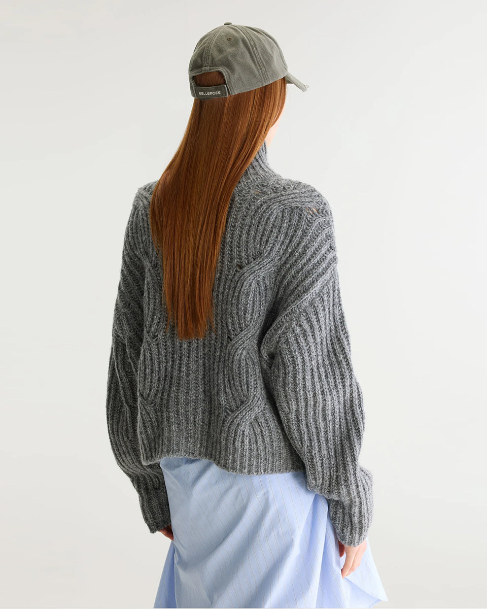 Szary sweter z golfem Deteo Mid Grey marki Bellerose o kroju oversize. Wykonany ściegiem typu "full cardigan", wyróżnia się bardzo grubym splotem ściągaczowym oraz dużymi wzorami warkoczowymi korpusie i rękawach.

-Krój oversize: celowo powiększony fason zapewniający obszerną, luźną sylwetkę

-Golf

-Warkoczowy splot&nbsp;