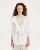 Luźna, biała bluzka Dolly White marki Antik Batik o swobodnym kroju, wyróżniającą się mocno romantycznym stylem boho. Z przodu jak i z tyłu posiada duży, ażurowy panel z misternej koronki o geometryczno- kwiatowym wzorze, który układa się w kształt litery V. Koronkowy dekolt zakończony jest szerokimi falbanami, które płynnie przechodzą w luźne, motylkowe rękawy o długości do łokcia. Z tyłu bluzka posiada subtelne rozcięcie w łezkę zapinane na guzik.&nbsp;

-Swobodny, luźny fason

-Falbany

-Koronka

-Zamów 
