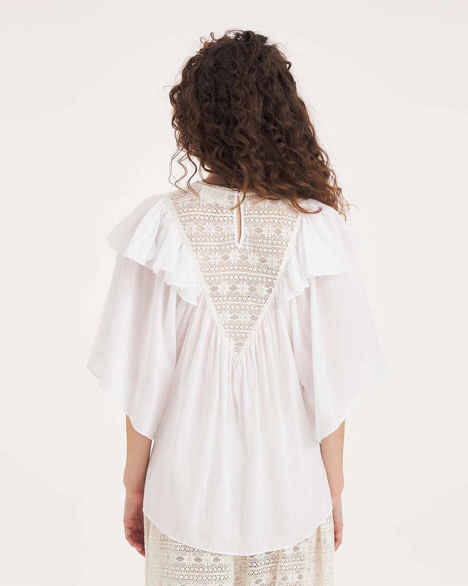 Luźna, biała bluzka Dolly White marki Antik Batik o swobodnym kroju, wyróżniającą się mocno romantycznym stylem boho. Z przodu jak i z tyłu posiada duży, ażurowy panel z misternej koronki o geometryczno- kwiatowym wzorze, który układa się w kształt litery V. Koronkowy dekolt zakończony jest szerokimi falbanami, które płynnie przechodzą w luźne, motylkowe rękawy o długości do łokcia. Z tyłu bluzka posiada subtelne rozcięcie w łezkę zapinane na guzik.&nbsp;

-Swobodny, luźny fason

-Falbany

-Koronka

-Zamów 