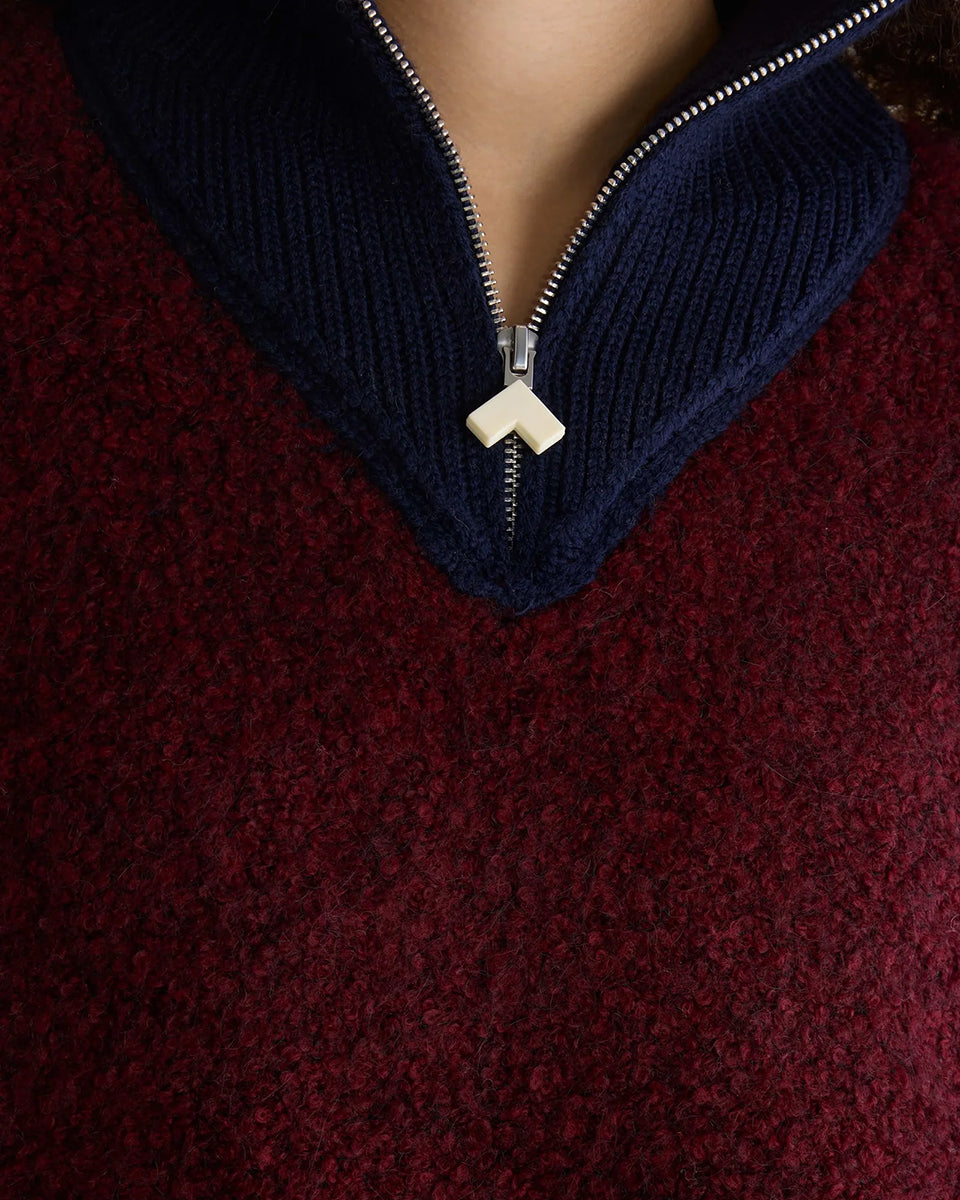 Sweter o klasycznym kroju z bordowej przędzy typu boucle Dooh Wine marki Bellerose wykonany splotem żakardowym imitującym fakturę ręcznika. Wyróżnia się kontrastowym, granatowym, podwójnym golfem z wełny merino, zapinanym na zamek błyskawiczny z uchwytem ozdobionym logo w kształcie serca.&nbsp;

-Krój regularny: zrównoważony fason, który podąża za naturalnymi liniami sylwetki

-Dwuwarstwowy golf zapinany na zamek

-Wyjątkowa przędza i splot żakardowy o fakturze ręcznika&nbsp;