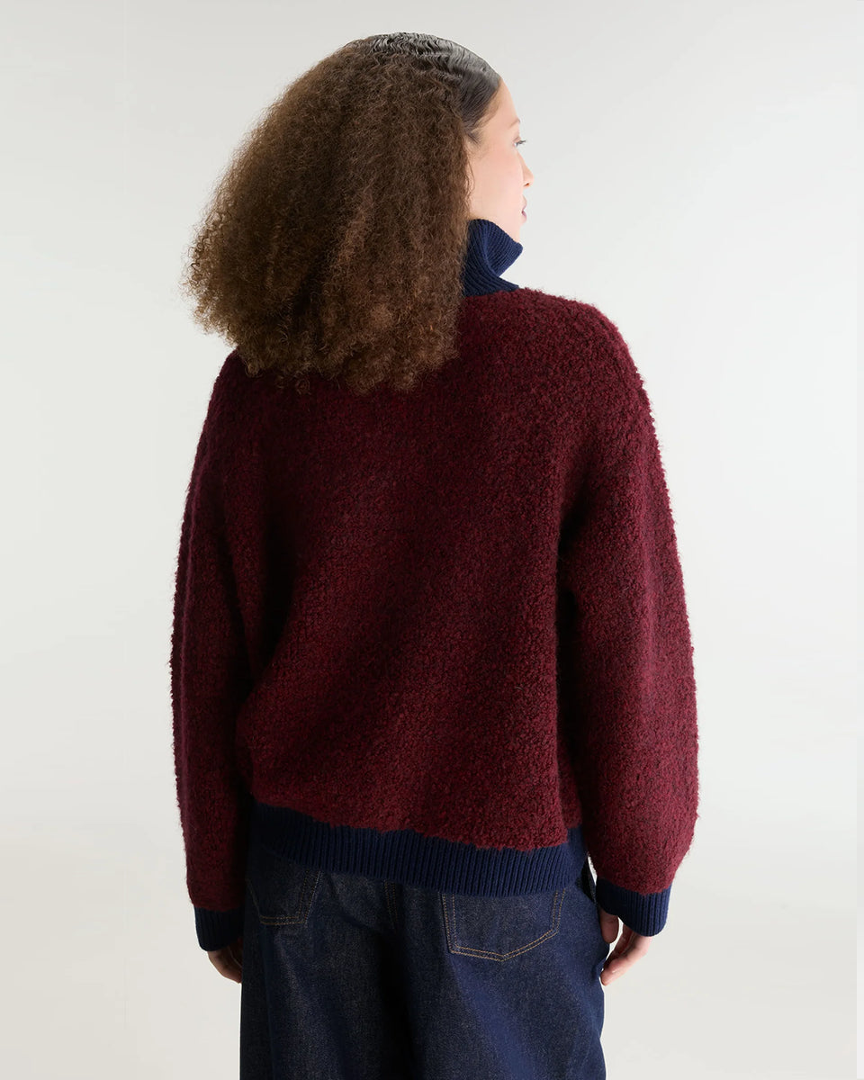 Sweter o klasycznym kroju z bordowej przędzy typu boucle Dooh Wine marki Bellerose wykonany splotem żakardowym imitującym fakturę ręcznika. Wyróżnia się kontrastowym, granatowym, podwójnym golfem z wełny merino, zapinanym na zamek błyskawiczny z uchwytem ozdobionym logo w kształcie serca.&nbsp;

-Krój regularny: zrównoważony fason, który podąża za naturalnymi liniami sylwetki

-Dwuwarstwowy golf zapinany na zamek

-Wyjątkowa przędza i splot żakardowy o fakturze ręcznika&nbsp;