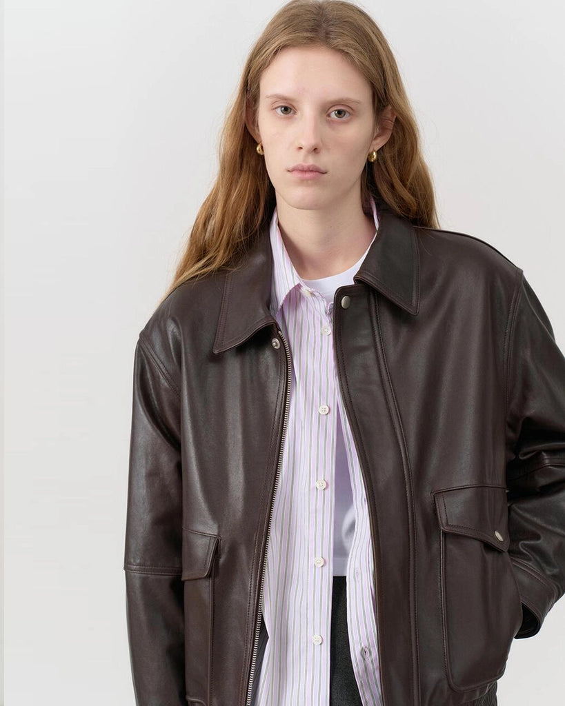 Luźna, brązowa skórzana kurtka Unisex Vintage Leather o prostym kroju i pudełkowym fasonie. Posiada kołnierzyk, luźne rękawy zapinane przy mankietach. Kurtka ma dwie, duże, prostokątne kieszenie z klapkami z przodu