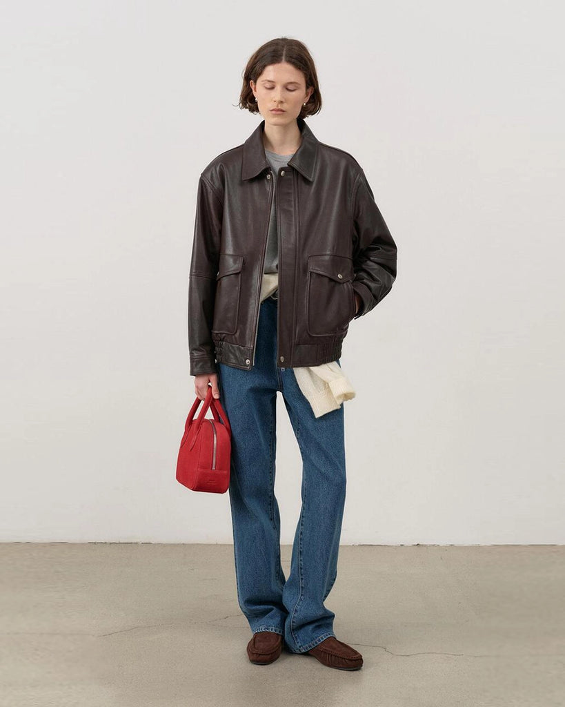 Luźna, brązowa skórzana kurtka Unisex Vintage Leather o prostym kroju i pudełkowym fasonie. Posiada kołnierzyk, luźne rękawy zapinane przy mankietach. Kurtka ma dwie, duże, prostokątne kieszenie z klapkami z przodu