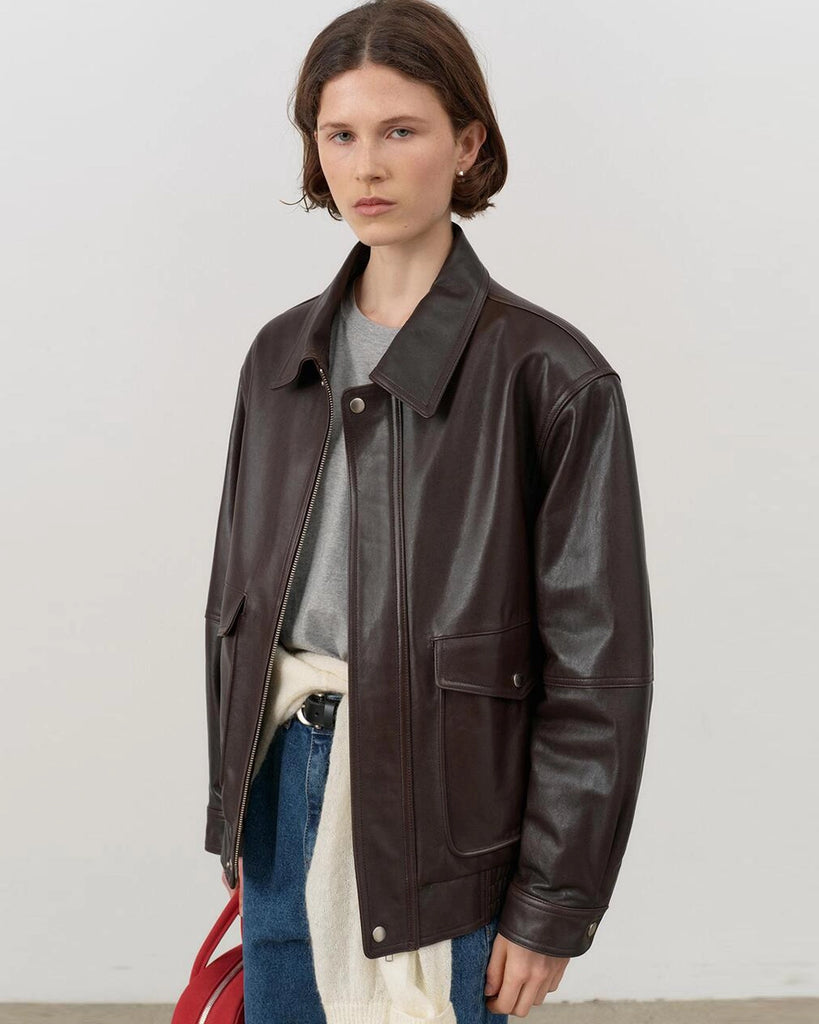 Luźna, brązowa skórzana kurtka Unisex Vintage Leather o prostym kroju i pudełkowym fasonie. Posiada kołnierzyk, luźne rękawy zapinane przy mankietach. Kurtka ma dwie, duże, prostokątne kieszenie z klapkami z przodu