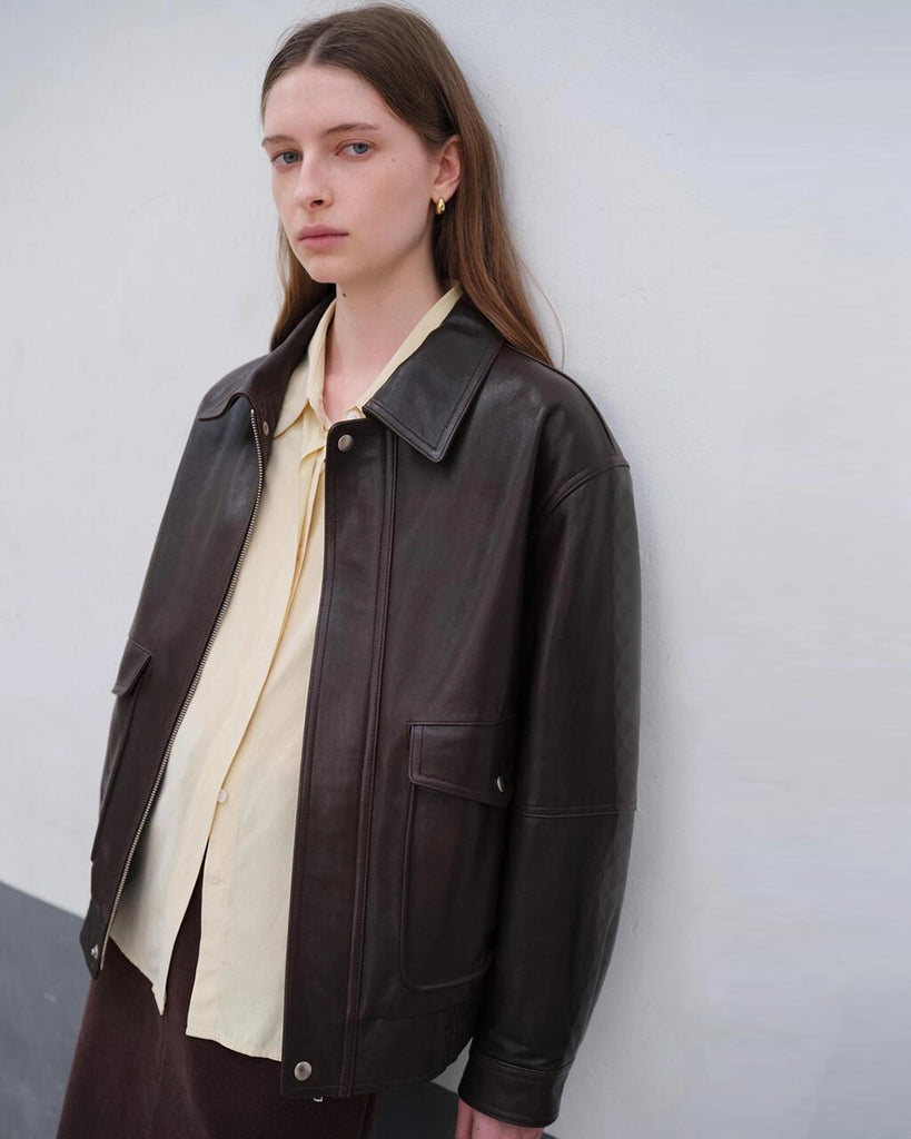 Luźna, brązowa skórzana kurtka Unisex Vintage Leather o prostym kroju i pudełkowym fasonie. Posiada kołnierzyk, luźne rękawy zapinane przy mankietach. Kurtka ma dwie, duże, prostokątne kieszenie z klapkami z przodu