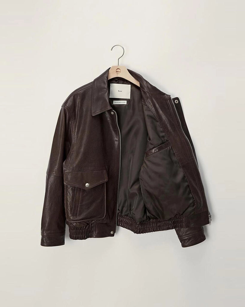 Luźna, brązowa skórzana kurtka Unisex Vintage Leather o prostym kroju i pudełkowym fasonie. Posiada kołnierzyk, luźne rękawy zapinane przy mankietach. Kurtka ma dwie, duże, prostokątne kieszenie z klapkami z przodu