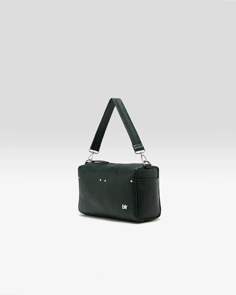 Torebka typu crossbody Duol Bottle Green marki BELLEROSE z teksturowanej, butelkowo-zielonej skóry koziej. Posiada regulowany, odpinany, beżowy pasek bawełniany oraz krótki, skórzany uchwyt. Zapinana na zamek błyskawiczny. Z przodu ma metalowe logo marki. Posiada wewnętrzną kieszeń główną, wewnętrzną kieszeń naszywaną oraz zewnętrzną kieszonkę boczną.&nbsp;