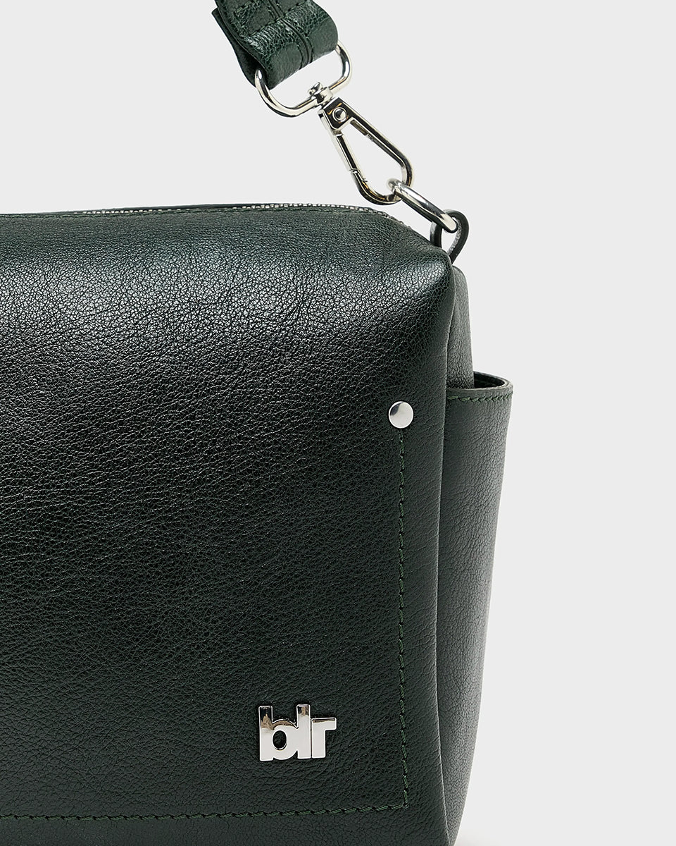 Torebka typu crossbody Duol Bottle Green marki BELLEROSE z teksturowanej, butelkowo-zielonej skóry koziej. Posiada regulowany, odpinany, beżowy pasek bawełniany oraz krótki, skórzany uchwyt. Zapinana na zamek błyskawiczny. Z przodu ma metalowe logo marki. Posiada wewnętrzną kieszeń główną, wewnętrzną kieszeń naszywaną oraz zewnętrzną kieszonkę boczną.&nbsp;