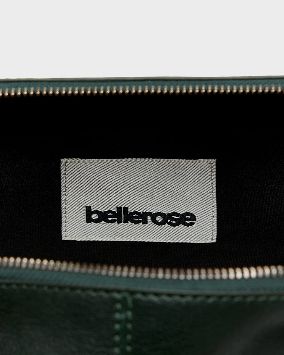 Torebka typu crossbody Duol Bottle Green marki BELLEROSE z teksturowanej, butelkowo-zielonej skóry koziej. Posiada regulowany, odpinany, beżowy pasek bawełniany oraz krótki, skórzany uchwyt. Zapinana na zamek błyskawiczny. Z przodu ma metalowe logo marki. Posiada wewnętrzną kieszeń główną, wewnętrzną kieszeń naszywaną oraz zewnętrzną kieszonkę boczną.&nbsp;