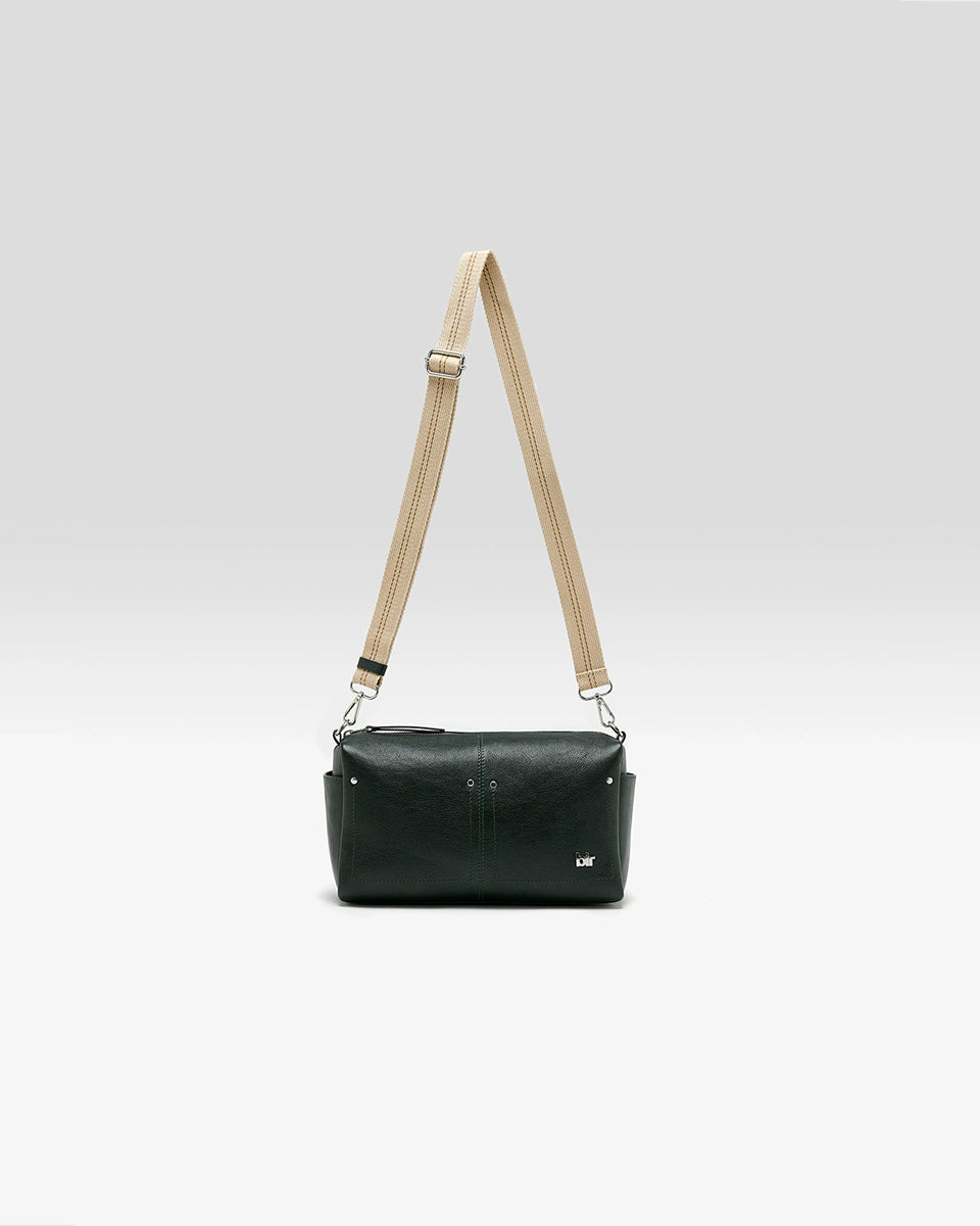 Torebka typu crossbody Duol Bottle Green marki BELLEROSE z teksturowanej, butelkowo-zielonej skóry koziej. Posiada regulowany, odpinany, beżowy pasek bawełniany oraz krótki, skórzany uchwyt. Zapinana na zamek błyskawiczny. Z przodu ma metalowe logo marki. Posiada wewnętrzną kieszeń główną, wewnętrzną kieszeń naszywaną oraz zewnętrzną kieszonkę boczną.&nbsp;