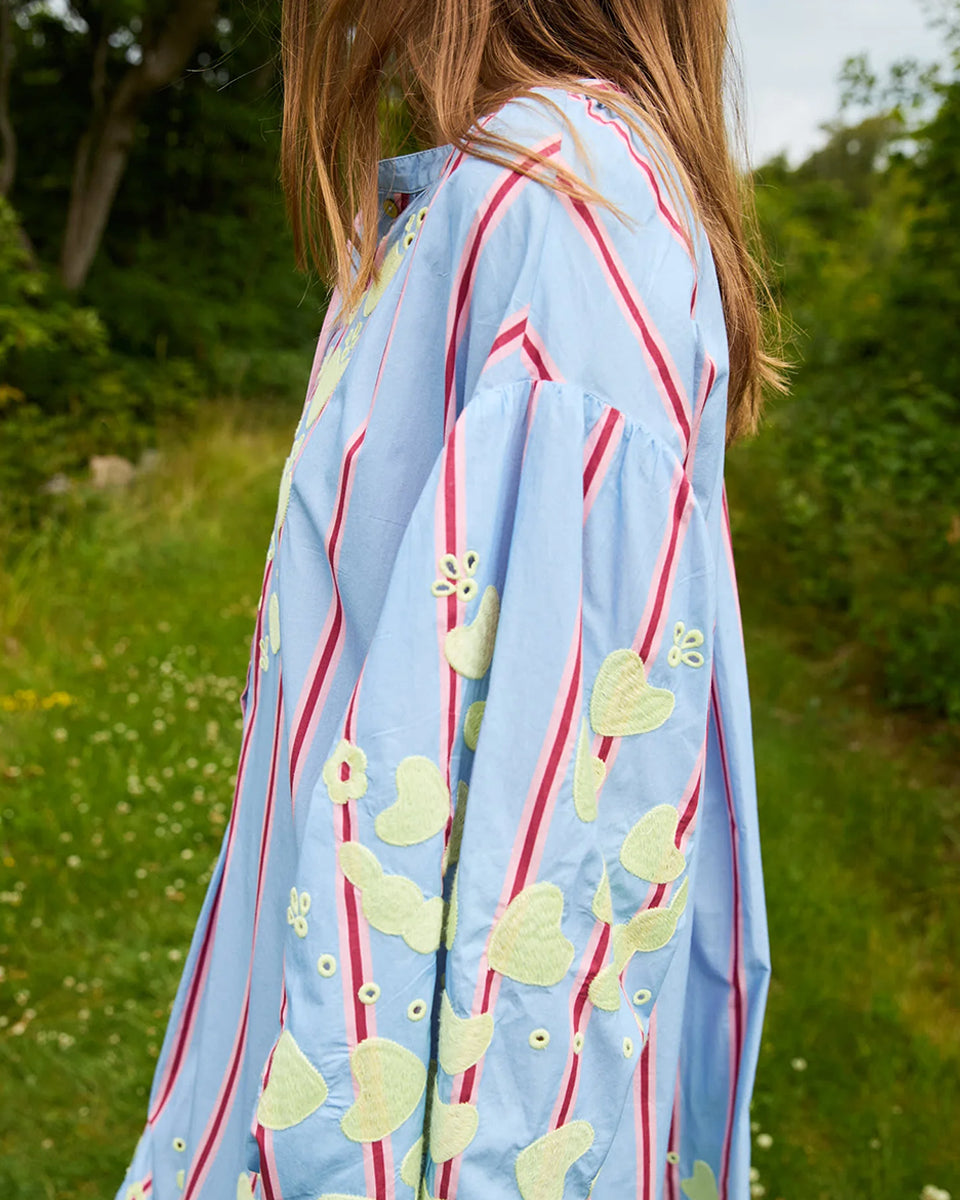 Haftowana, oversizowa sukienka maxi w czerwono-różowe paski Elisabeth Bluebell Stripes SISSEL EDELBO z długimi, szerokimi rękawami i opadającymi ramionami. Mankiety rękawów są zwężane i wykończone uroczą falbanką. Sukienka ma okrągły dekolt. Na dekolcie zapinana jest za pomocą drobnych guzików z masy perłowej. Wykonana jest ze zwiewnej bawełny organicznej z haftem z motywem serc. Posiada długość przed kostki.

-ONE SIZE

-Oversize

-100% bawełna organiczna