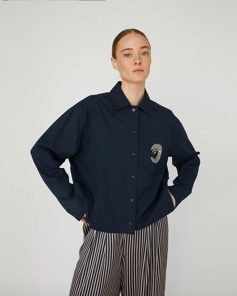 Luźna, granatowa koszula Embellished Moon Navy marki STELLA NOVA z długimi rękawami i mankietem. Ma klasyczny kołnierzyk i zapięcie na guziki z przodu. Na lewej piersi posiada kieszeń z wyhaftowanym księżycem.&nbsp;
