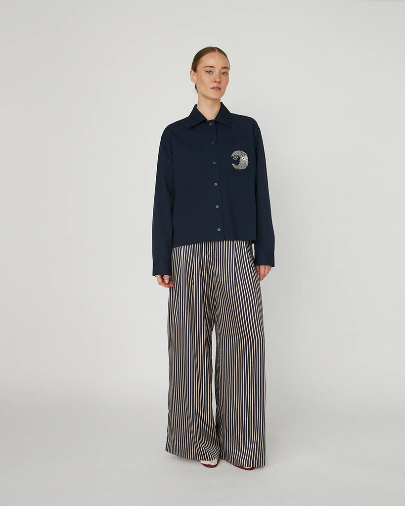 Luźna, granatowa koszula Embellished Moon Navy marki STELLA NOVA z długimi rękawami i mankietem. Ma klasyczny kołnierzyk i zapięcie na guziki z przodu. Na lewej piersi posiada kieszeń z wyhaftowanym księżycem.&nbsp;
