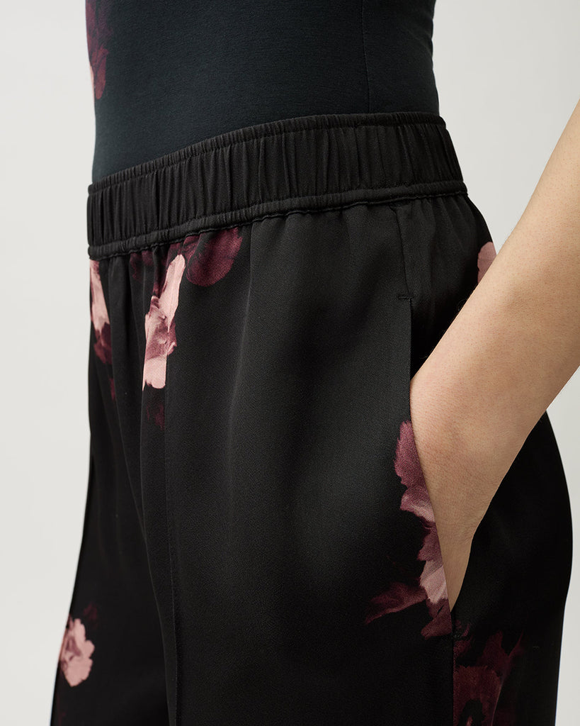 Zwiewne, lejące spodnie Ezra Wine Black w kwiatowy print z elastycznym pasem na gumce i kieszeniami po bokach. Mają wysoki stan i rozszerzaną nogawkę.&nbsp;