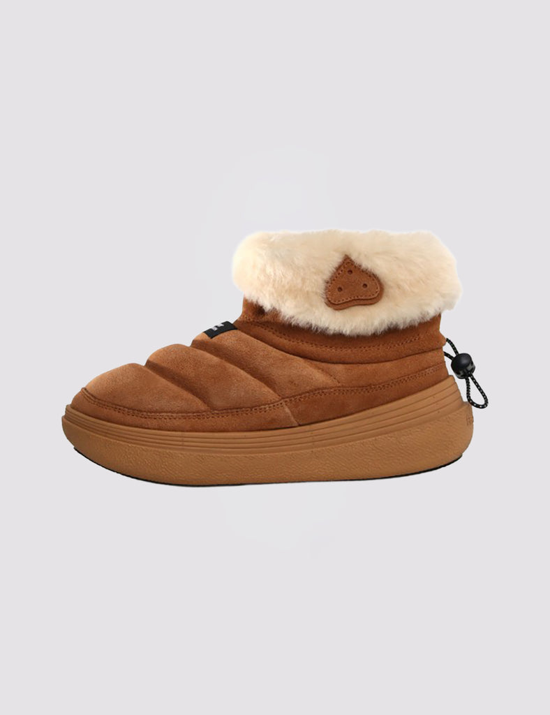 Zamszowe botki Fami Mid Shearling Brown z podszewką z owczej skóry są połączeniem wysokich trampek i kapci. Charakteryzują się kokosowymi liniami i delikatną wyściółką na zamszowej cholewce. Mają wkładkę z korka, gumową podeszwę i zapięcie na kostce z małym ściągaczem i gumowym obszyciem. Idealne na zimę.
