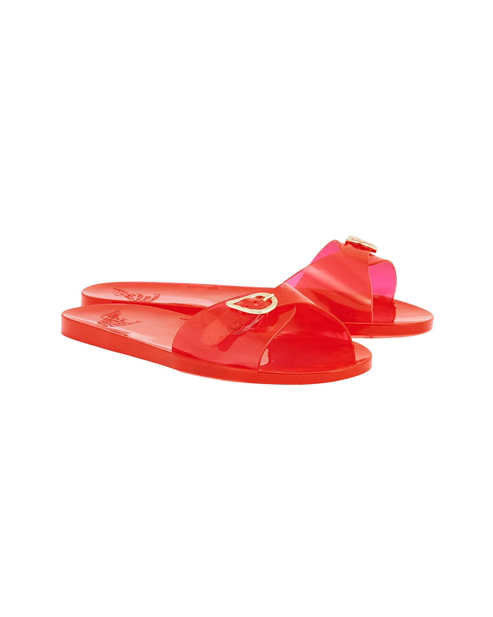 Swobodne, minimalistyczne klapki typu slide Filia Jelly Red na całkowicie płaskiej podeszwie. Mają intensywny odcień czerwieni, o półprzezroczystym wykończeniu. Posiadają jeden, szeroki, asymetryczny pasek ze złotą klamrą w kształcie skrzydełek. Na wkładce widoczne jest wytłoczone logo marki. Wykonane z elastycznej, wodoodpornej gumy/PVC, co czyni je idealnym wyborem jako stylowe obuwie plażowe.&nbsp;