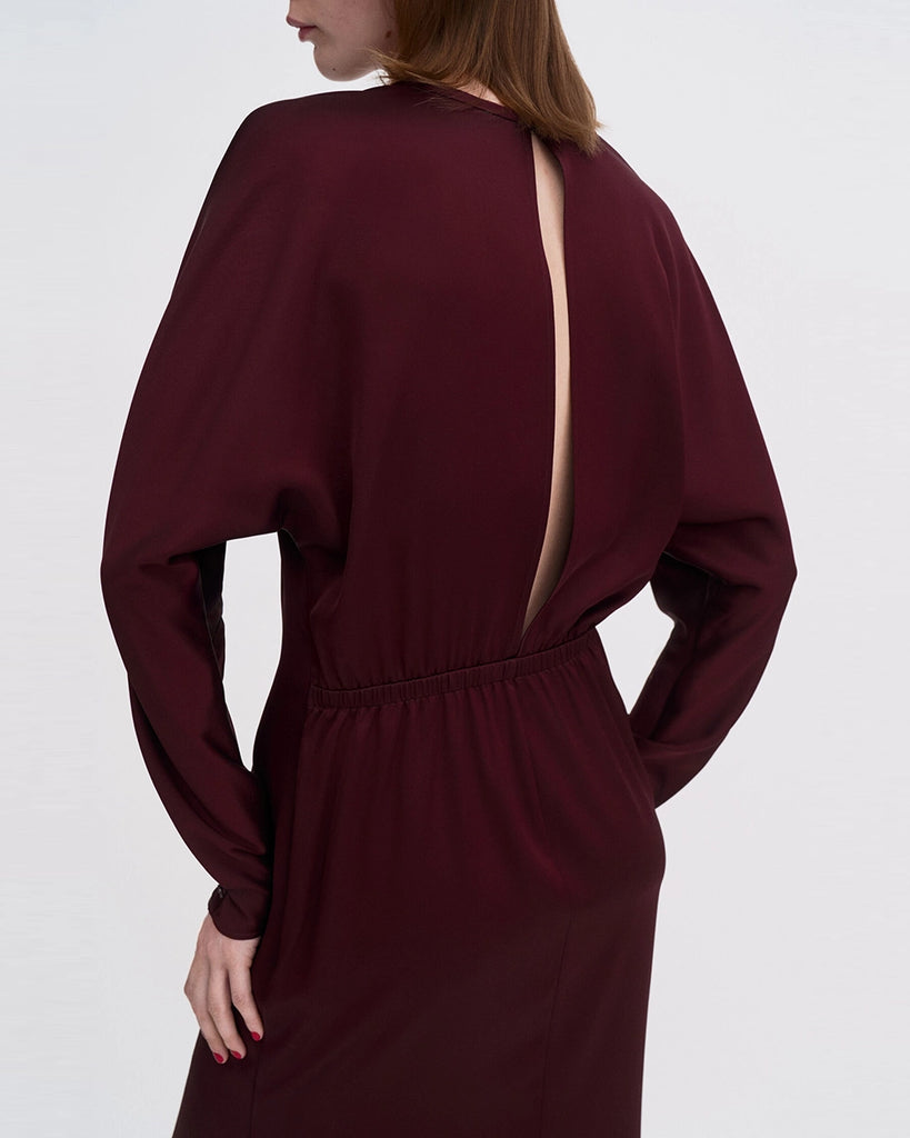 Minimalistyczna, luźna, elegancka sukienka midi Filippa K z okrągłym dekoltem i długimi rękawami rozszerzanymi pod pachami z guzikami przy mankietach. Na plecach posiada długie, wąskie rozcięcie. Z tyłu przy szyi zapinana na jeden guzik. Lekko zwężana w talii. Z tyłu w pasie ma elastyczną gumkę.