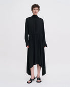 Minimalistyczna, luźna, elegancka sukienka midi Filippa K z wysokim dekoltem w formie golfu i wiązaniem z tyłu przy szyi. Sukienka ma długie rękawy zakończone mankietami oraz efektowne, wąskie rozcięcie na plecach. Z przodu marszczona przy dekolcie i i talii. U dołu wykończona asymetrycznie