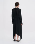 Minimalistyczna, luźna, elegancka sukienka midi Filippa K z wysokim dekoltem w formie golfu i wiązaniem z tyłu przy szyi. Sukienka ma długie rękawy zakończone mankietami oraz efektowne, wąskie rozcięcie na plecach. Z przodu marszczona przy dekolcie i i talii. U dołu wykończona asymetrycznie