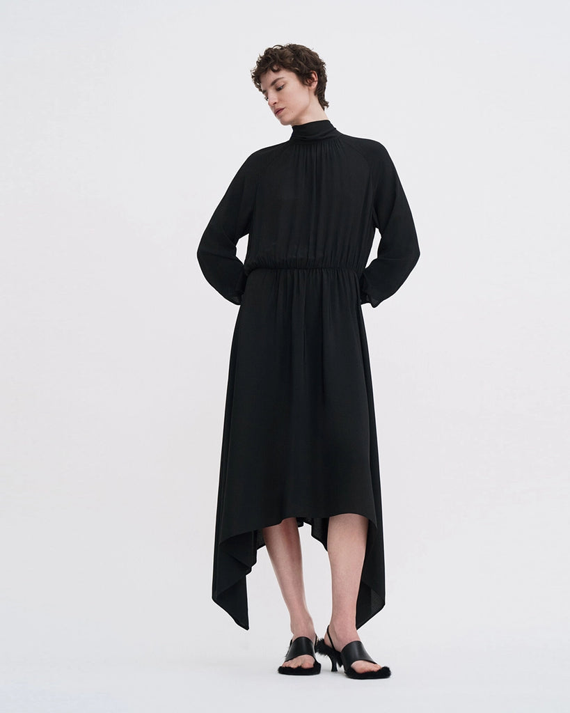 Minimalistyczna, luźna, elegancka sukienka midi Filippa K z wysokim dekoltem w formie golfu i wiązaniem z tyłu przy szyi. Sukienka ma długie rękawy zakończone mankietami oraz efektowne, wąskie rozcięcie na plecach. Z przodu marszczona przy dekolcie i i talii. U dołu wykończona asymetrycznie