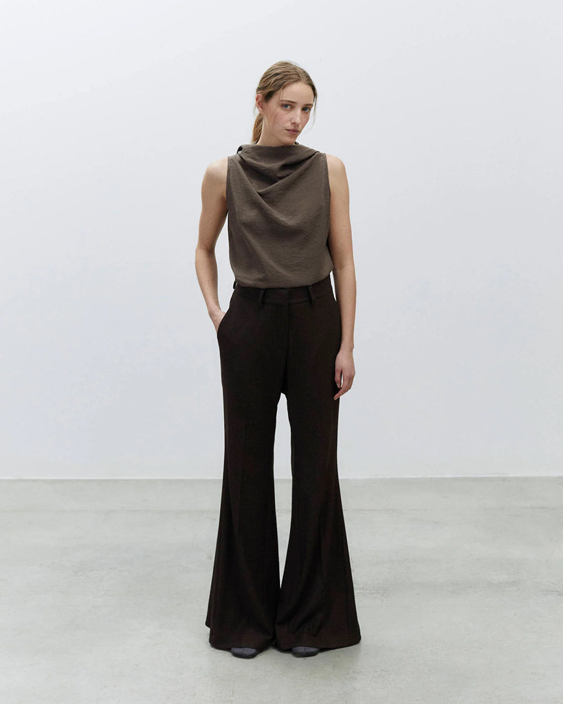 Spodnie dzwony Flare Lana Choco o regularnym kroju z wysokim stanem. Posiadają szlufki na pasek, kieszenie boczne z przodu i tylne kieszenie z patką zapinane na guziki. Wykonane z mieszanki z wiskozą i wełną. Zapinane na kryty zamek błyskawiczny i haftkę.&nbsp;