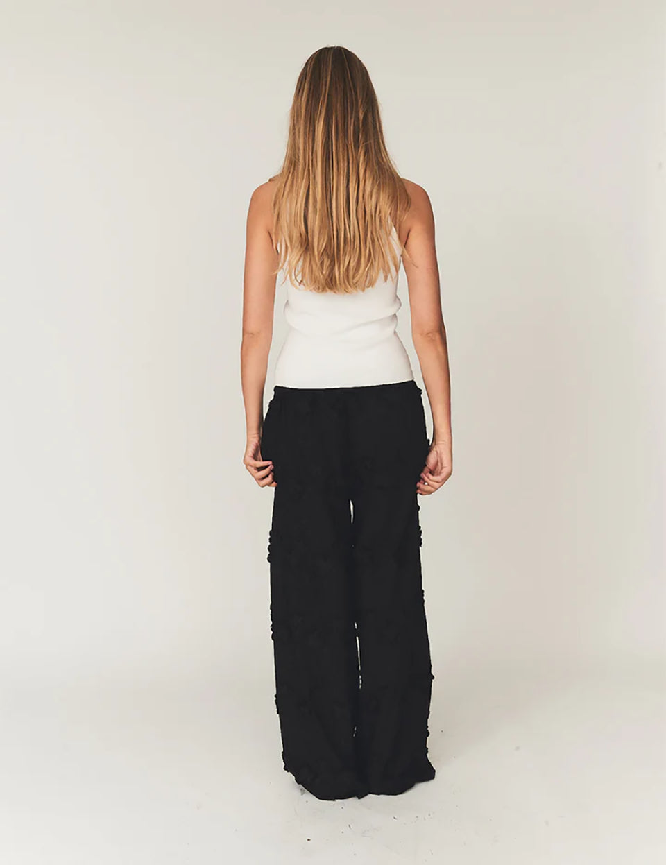 Luźne, proste, czarne spodnie Fleur Black marki The Garment z długimi, szerokimi nogawkami i elastyczną talią z gumką w pasie. Na całej powierzchni naszyte są wypukłe, kwiatowe aplikacje 3D. Dół nogawek wykończony jest naturalnym, falistym brzegiem koronki. Te spodnie to idealna alternatywa dla klasycznej sukienki wieczorowej.

-Luźny krój typu wide-leg

-Wypukłe, kwiatowe aplikacje

-Zamów spodnie w swoim normalnym rozmiarze