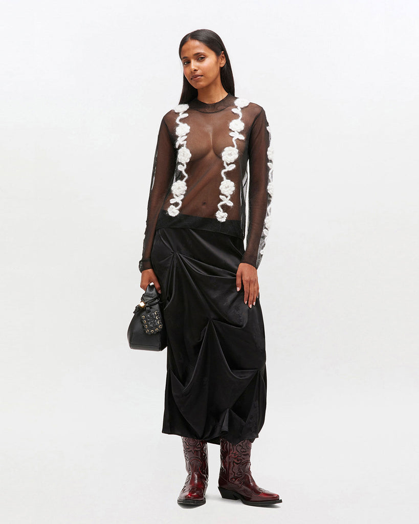 Transparentny, czarny top 2649 Ganni Black z długim rękawem i wysokim, okrągłym kołnierzykiem. Posiada zdobienia w postaci kwiatów wykonanych szydełkiem. Idealny do długiej spódnicy na eleganckie okazje.