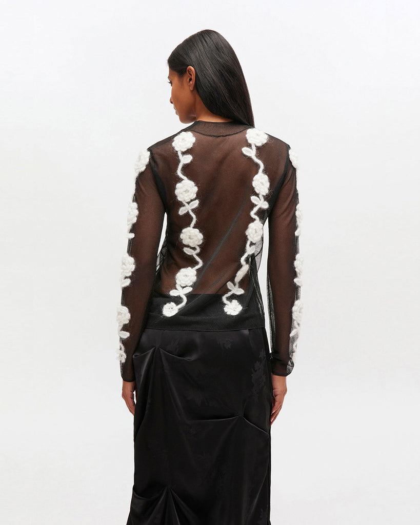 Transparentny, czarny top 2649 Ganni Black z długim rękawem i wysokim, okrągłym kołnierzykiem. Posiada zdobienia w postaci kwiatów wykonanych szydełkiem. Idealny do długiej spódnicy na eleganckie okazje.