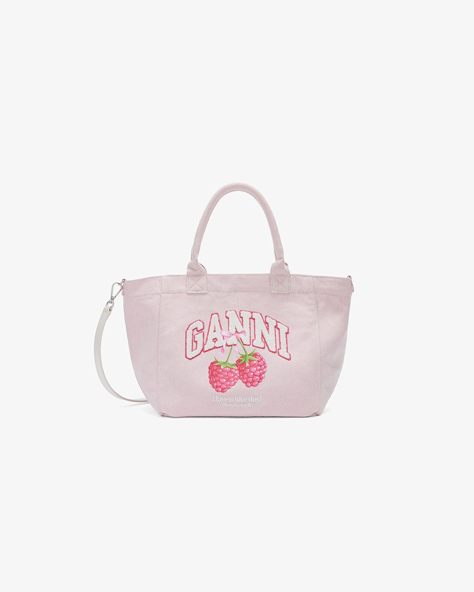 Mała, trapezowa, różowa torba shopper 2110 Rasperry GANNI z pluszowym logo marki oraz z uroczym printem z motywem malin. Torba posiada dwie, grube, krótkie rączki do wygodnego trzymania w dłoni oraz odpinany, cienki, długi pasek do wygodnego zawiedzenia na ramieniu. Wewnątrz znajduje się mała kieszonka zapinana na zamek błyskawiczny. Wykonana z grubego, sztywnego, płóciennego materiału.