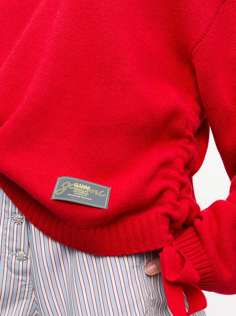 Oversizowy, długi sweter 2477 Future Wool GANNI z okrągłym dekoltem i szerokimi, długimi rękawami i opadającymi ramionami. Po bokach posiada marszczenia i wiązania. U dołu sweter ma niewielką naszywkę z logo marki. 