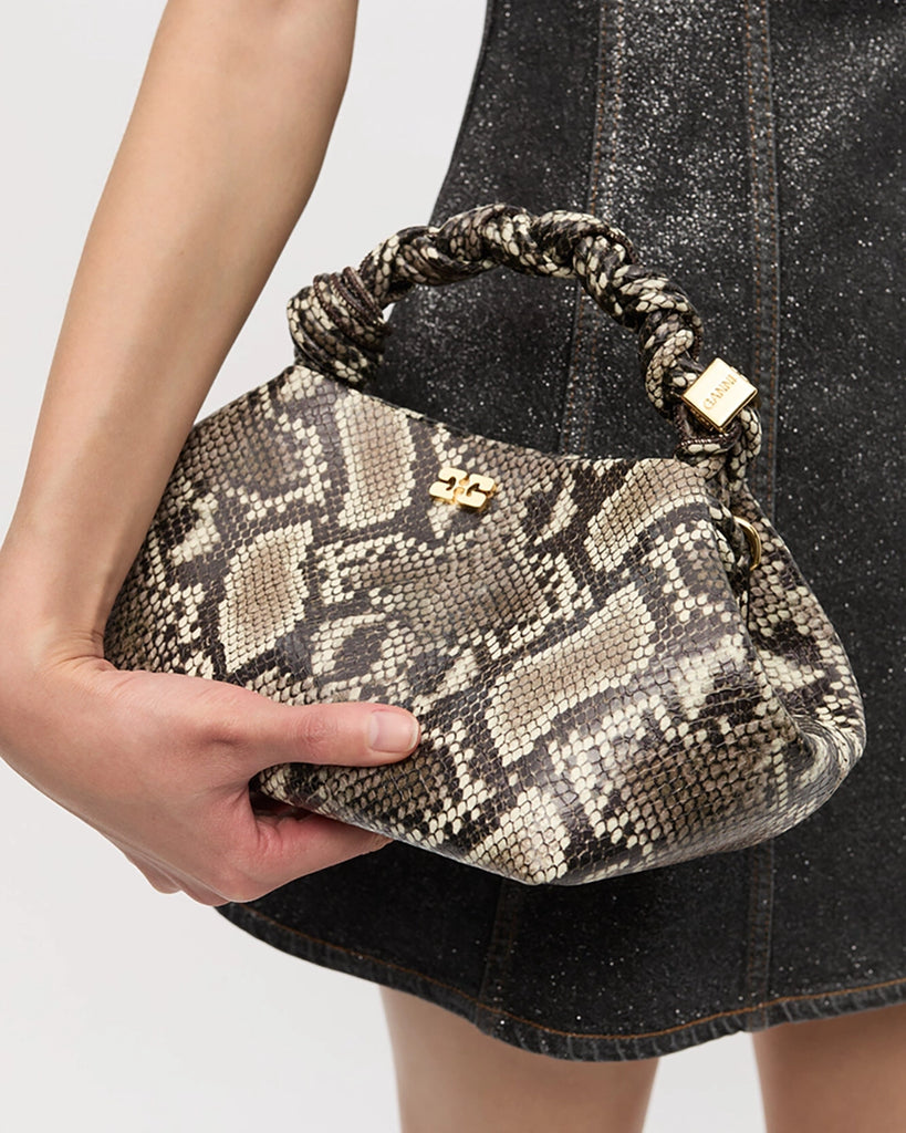 Niewielka torebka Bou Small 6758 GANNI w wężowy print o trapezowym kształcie z plecioną, krótką rączką i odpinanym długim, cienkim paskiem o regulowanej długości.