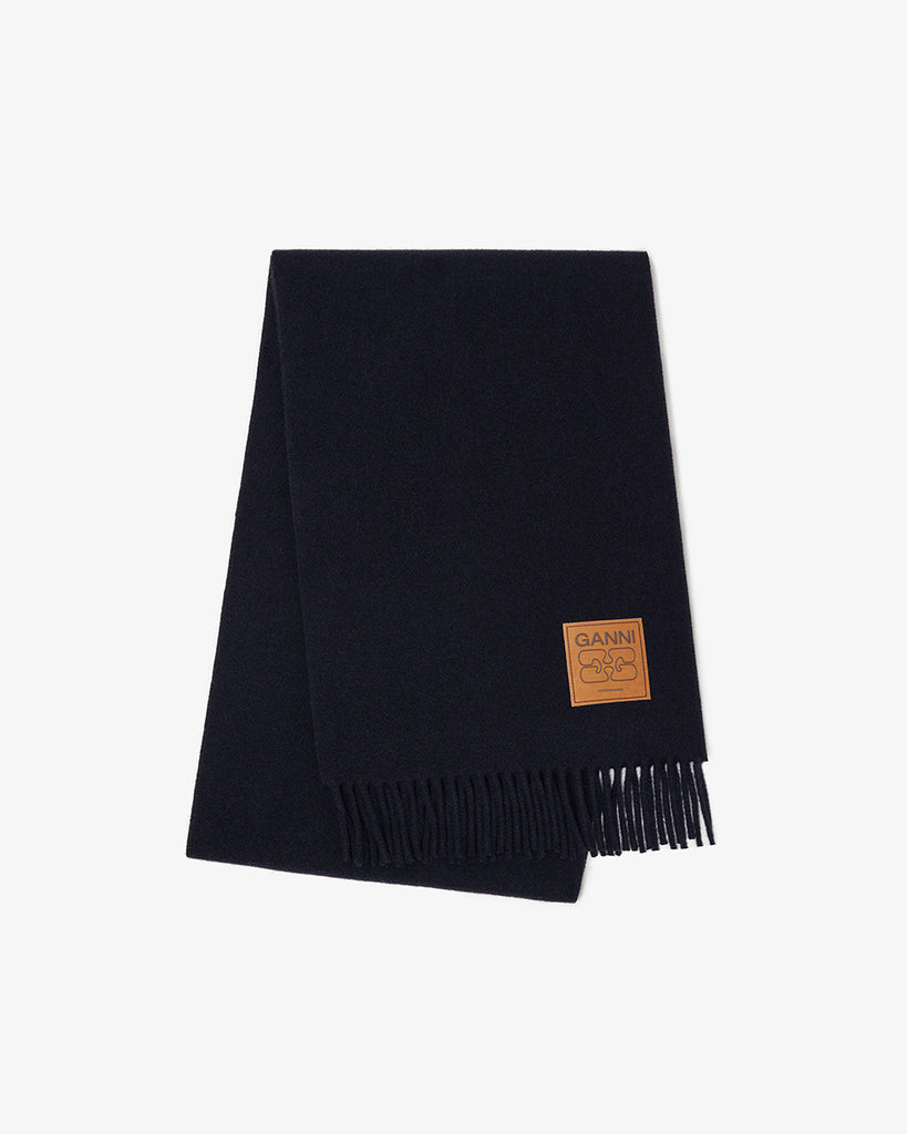 Dzianinowy, ciepły szalik 6931 Ganni Sky Captain w kolorze granatowym, z frędzlami u dołu i naszywką z logo marki. Wykonany z wełny.&nbsp;