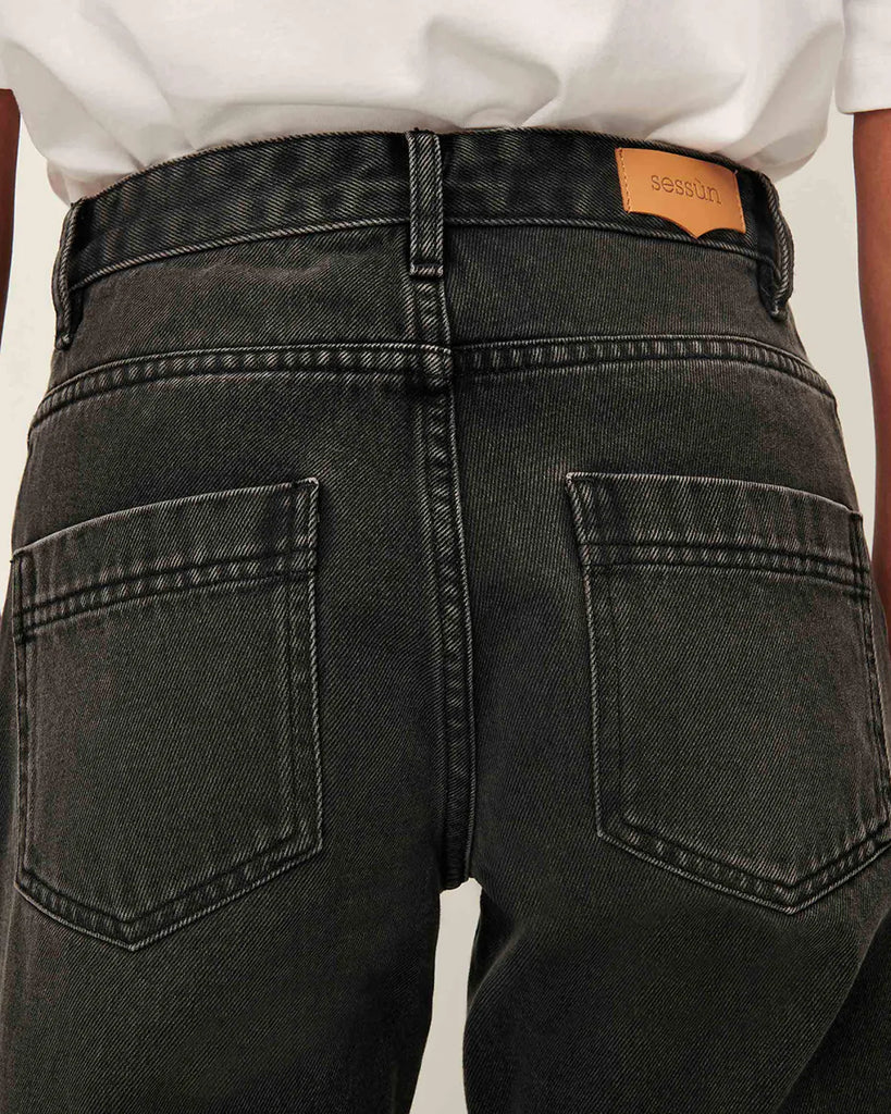 Długie Jeansy Garett Wash marki Sessun w kolorze szarym, ze średnim stanem i prostą, wydłużoną nogawką. Zapinane na ukryte guziki. Mają kieszenie z przodu oraz z tyłu i wytłoczoną, skórzaną naszywkę z logo marki. Wykonane są z grubego denimu stonewash.
