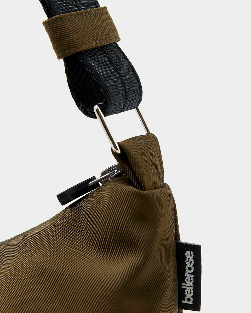 Mała torba typu sling w kolorze khaki Hane Carbone marki Bellerose o miękkiej, zaokrąglonej konstrukcji. Model wyposażony w zapięcie na zamek błyskawiczny; szeroki, regulowany pasek z taśmy, srebrne okucia i wewnętrzną kieszeń. Posiada podszewkę z lekkiego materiału technicznego.&nbsp;