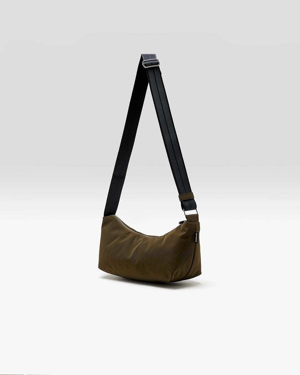 Mała torba typu sling w kolorze khaki Hane Carbone marki Bellerose o miękkiej, zaokrąglonej konstrukcji. Model wyposażony w zapięcie na zamek błyskawiczny; szeroki, regulowany pasek z taśmy, srebrne okucia i wewnętrzną kieszeń. Posiada podszewkę z lekkiego materiału technicznego.&nbsp;