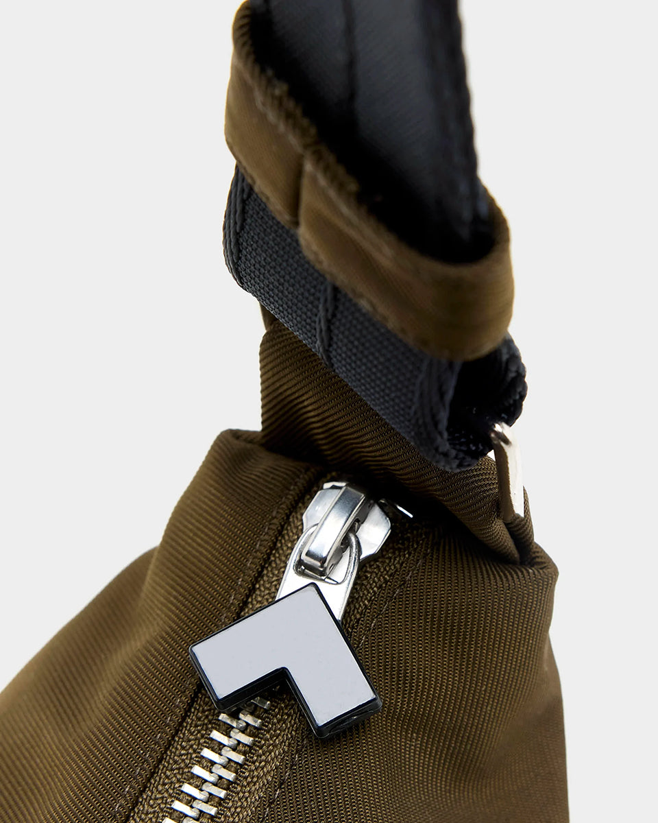 Mała torba typu sling w kolorze khaki Hane Carbone marki Bellerose o miękkiej, zaokrąglonej konstrukcji. Model wyposażony w zapięcie na zamek błyskawiczny; szeroki, regulowany pasek z taśmy, srebrne okucia i wewnętrzną kieszeń. Posiada podszewkę z lekkiego materiału technicznego.&nbsp;