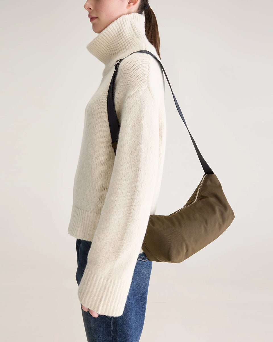 Mała torba typu sling w kolorze khaki Hane Carbone marki Bellerose o miękkiej, zaokrąglonej konstrukcji. Model wyposażony w zapięcie na zamek błyskawiczny; szeroki, regulowany pasek z taśmy, srebrne okucia i wewnętrzną kieszeń. Posiada podszewkę z lekkiego materiału technicznego.&nbsp;