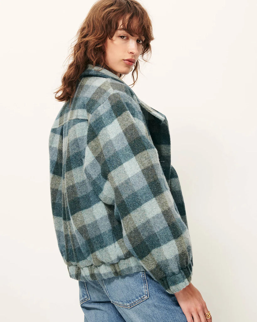 Krótki, elastyczny płaszcz Harlow Smocky Blue z miękkiej, puszystej wełny o podwójnym splocie w kratę, tkanej we Włoszech. Ma wysoki kołnierz z zapięciem na guzik, kieszenie z patką oraz ściągacz na dole i przy mankietach. Zapięcie dwurzędowe.&nbsp;