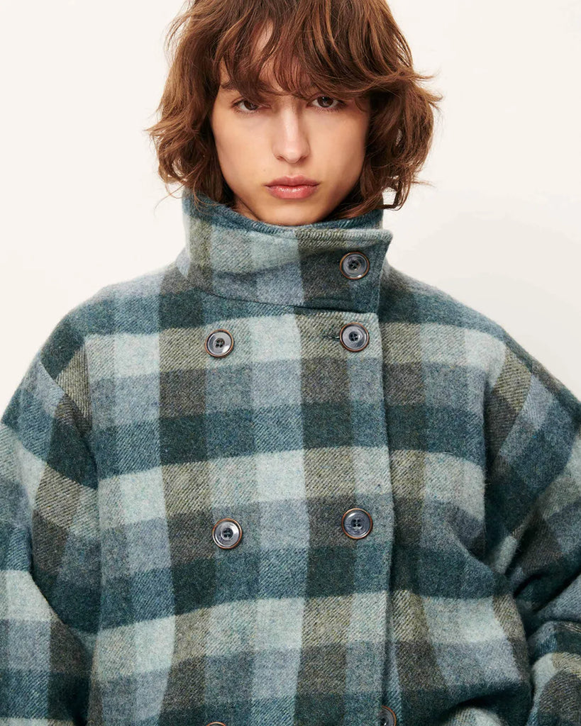 Krótki, elastyczny płaszcz Harlow Smocky Blue z miękkiej, puszystej wełny o podwójnym splocie w kratę, tkanej we Włoszech. Ma wysoki kołnierz z zapięciem na guzik, kieszenie z patką oraz ściągacz na dole i przy mankietach. Zapięcie dwurzędowe.&nbsp;