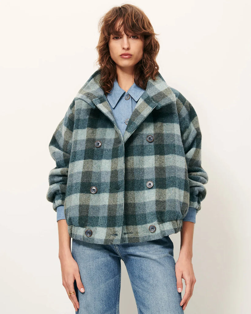 Krótki, elastyczny płaszcz Harlow Smocky Blue z miękkiej, puszystej wełny o podwójnym splocie w kratę, tkanej we Włoszech. Ma wysoki kołnierz z zapięciem na guzik, kieszenie z patką oraz ściągacz na dole i przy mankietach. Zapięcie dwurzędowe.&nbsp;