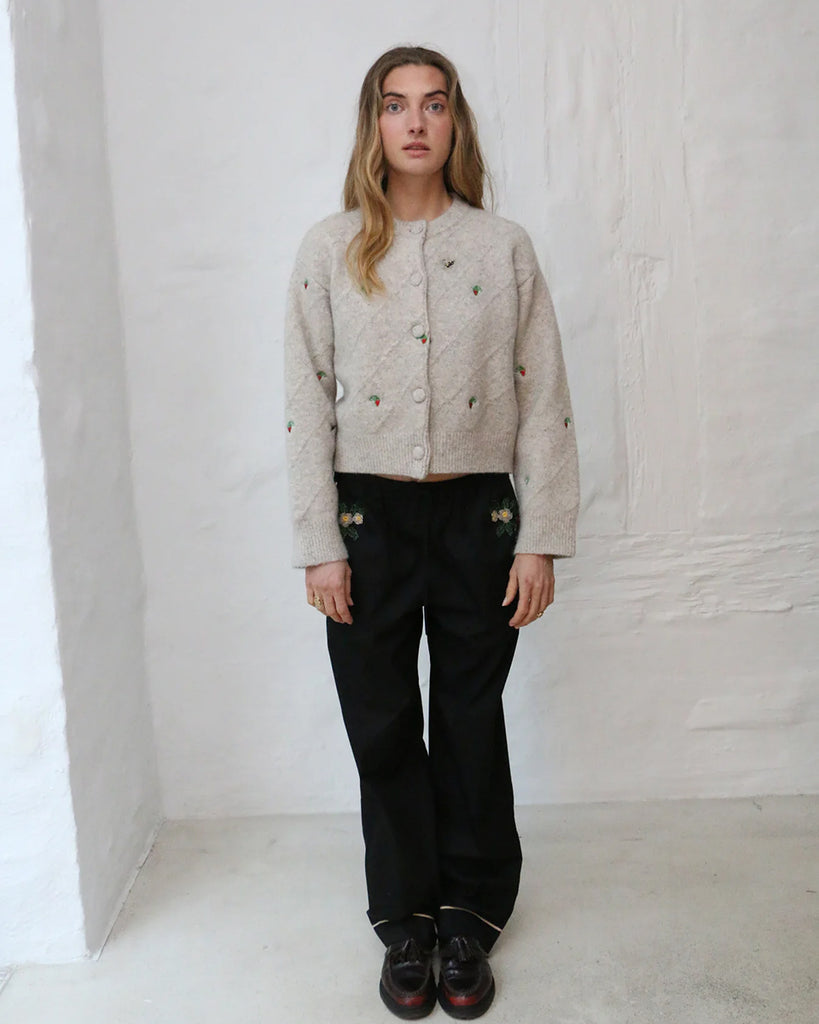 Luźny kardigan Maja HELMSTEDT o pudełkowym fasonie z okrągłym dekoltem i szerokimi rękawami. Haftowany ręcznie w uroczy motyw z drobnymi poziomkami i pszczołami. Zapinany na guziki obszyte dzianiną.